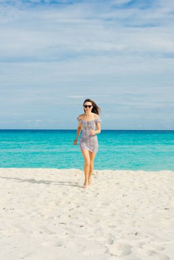 Yalnız ve çekici bir kız, saçlarında rüzgarla sakin denize bakıyor.