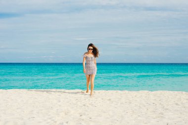 Yalnız ve çekici bir kız, saçlarında rüzgarla sakin denize bakıyor.