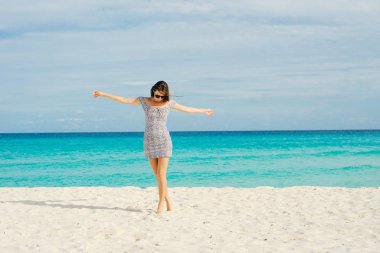 Yalnız ve çekici bir kız, saçlarında rüzgarla sakin denize bakıyor.