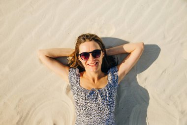 Gözlüklü kız plajda uzanarak dinleniyor. en üstteki görünüm