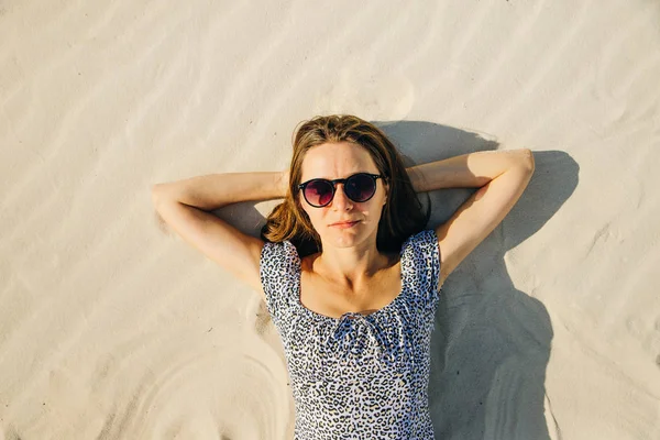 Gözlüklü kız plajda uzanarak dinleniyor. en üstteki görünüm