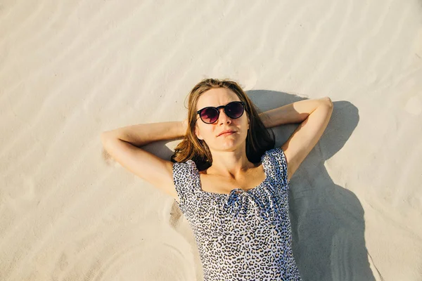 Girl with glasses is relaxing by laying down on the beach. top view — Stock Photo, Image