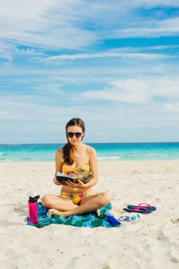 Yaz tatili. Turist kadınların rahatlama ve plajda güneş gözlükleriyle kitap okumaları.
