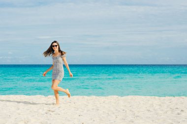 Yalnız ve çekici bir kız, saçlarında rüzgarla sakin denize bakıyor.