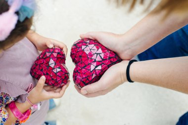 Bir çocuk ve annenin ellerinde kırmızı kalpler. Yukarıdan görünüm