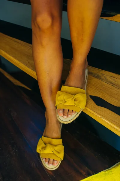 Legs of a girl in yellow shoes on a wooden floor — Stock Photo, Image