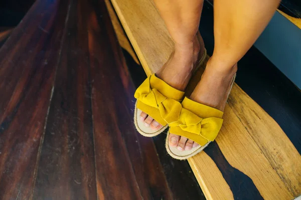 Pernas de uma menina em sapatos amarelos em um chão de madeira — Fotografia de Stock