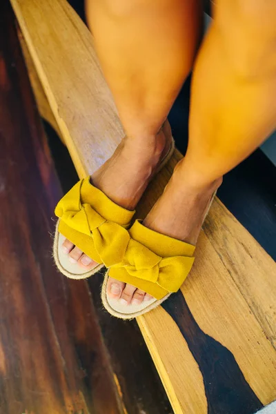 Legs of a girl in yellow shoes on a wooden floor — Stock Photo, Image