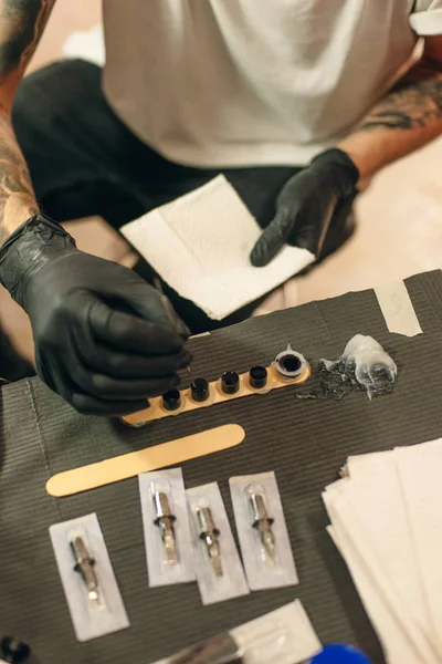 Tatuaje artista lugar de trabajo con máquina y botellas con tinta de tatuaje negro —  Fotos de Stock