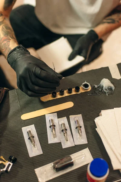 Tattoo artist workplace with machine and bottles with black tattoo ink