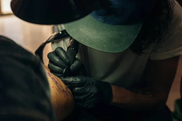 Close up af professionel tattooer kunstner gør billede på hånden af mand ved maskine sort blæk fra en krukke . - Stock-foto