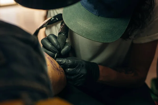 Close up af professionel tattooer kunstner gør billede på hånden af mand ved maskine sort blæk fra en krukke . - Stock-foto