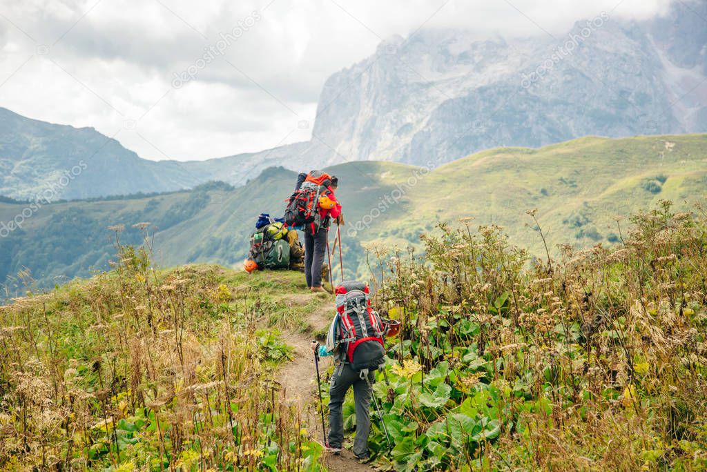 Group hiking in the mountains with large backpacks. Russia.