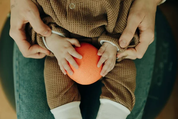 赤ん坊は腕の中にオレンジを持っていて — ストック写真