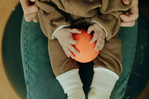 赤ん坊は腕の中にオレンジを持っていて — ストック写真