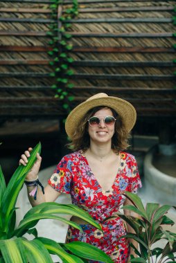 Kırmızı şapkalı ve renkli pelerinli bir kız puf puf üzerinde oturuyor..