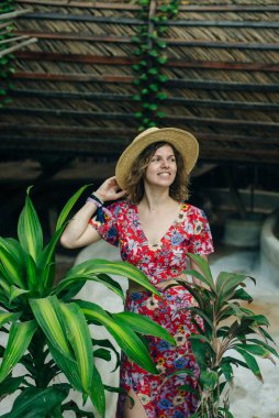 Kırmızı şapkalı ve renkli pelerinli bir kız puf puf üzerinde oturuyor..