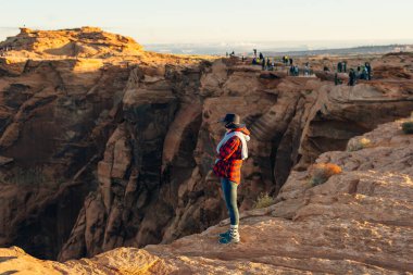 Sarışın kız, Glen Canyon Ulusal Eğlence Bölgesi 'nde sabah erkenden at nalı bükme yerinde oturuyor..