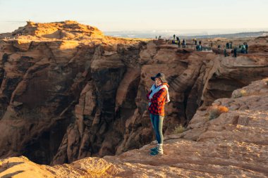 Sarışın kız, Glen Canyon Ulusal Eğlence Bölgesi 'nde sabah erkenden at nalı bükme yerinde oturuyor..