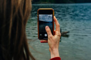 Kız telefondaki suda vahşi kuşların fotoğrafını çekiyor..