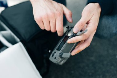 Uzaktan kumanda. Uzaktan kumandalı adam. Adam uzaktan kumandayı elleriyle tutuyor ve insansız hava aracını kontrol ediyor.