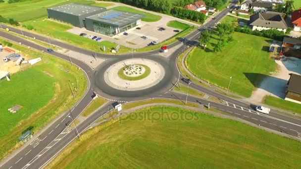 Letecký pohled, auta jezdí od kruhového objezdu na náměstí venkovské silnici. Rakousko, Evropa. — Stock video