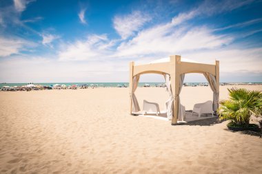 Sahilde beyaz sandalye ile çardak.