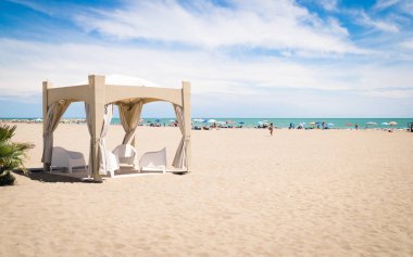 Sahilde beyaz sandalye ile çardak.