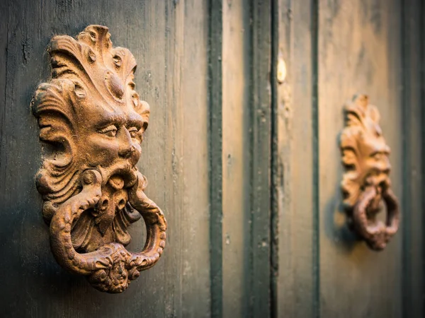 Arany ajtó kopogtatók egy régi ajtó, Olaszország. — Stock Fotó