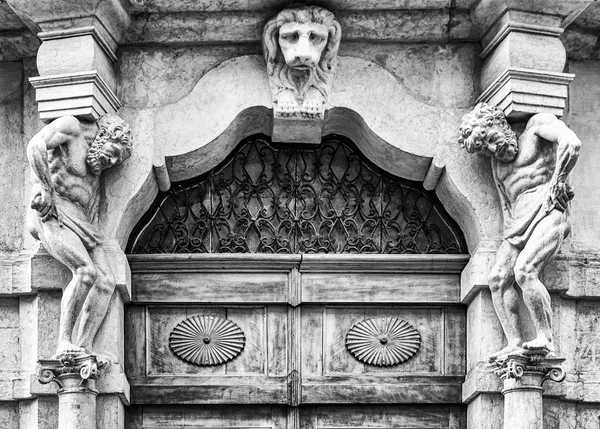 Antigua entrada de piedra blanca con estatuas y portal de madera . — Foto de Stock