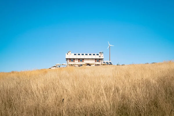 Cabaña alpina con paneles fotovoltaicos y generador eólico . —  Fotos de Stock