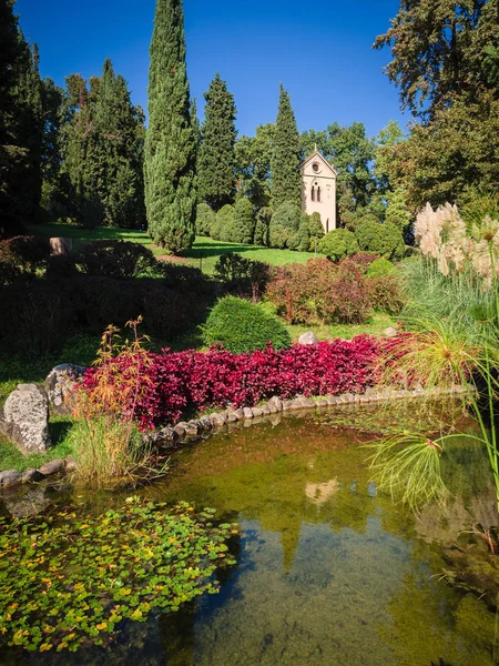 Belo jardim com lagoa e pequena igreja . — Fotografia de Stock