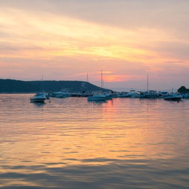 Ateşli günbatımı marina denizde yansıtır.