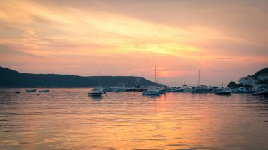 Ateşli günbatımı küçük bir marina denizde yansıtır.