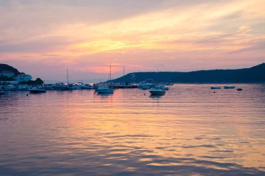 Ateşli günbatımı küçük bir marina denizde yansıtır.