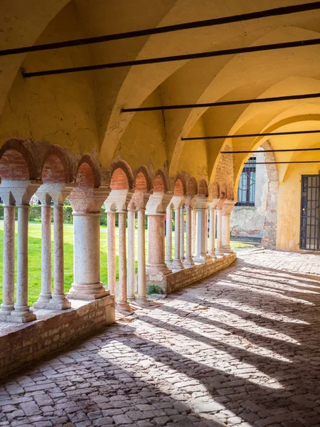 Avluda beyaz taş sütunlarla kemerli sundurma.