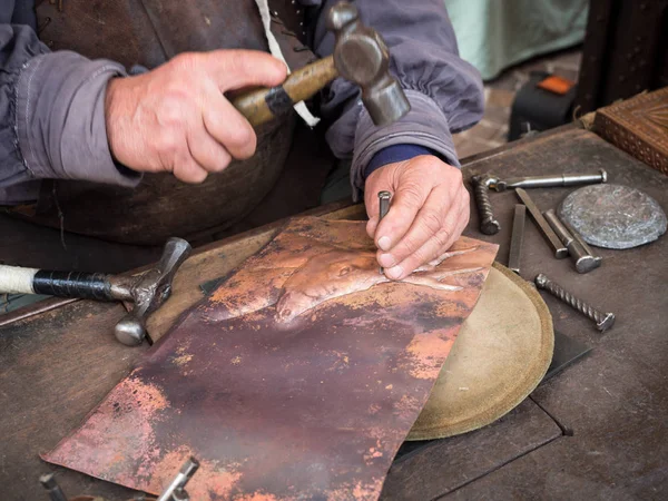 Detalle de un artesano graba una placa de cobre con un martillo y — Foto de Stock