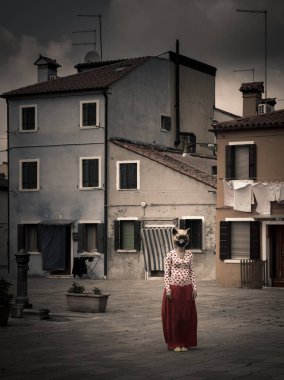 Burano, İtalya - 23 Nisan 2017 Venedik gölündeki eski bir meydanda kedi maskeli bir kadın. Korku ve rahatsızlık yaratan sahne..