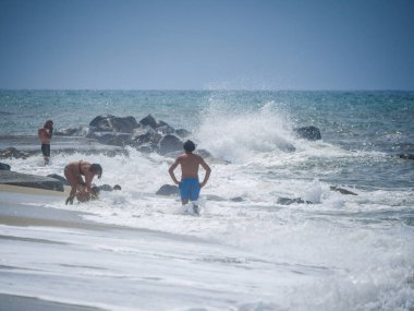 Şiddetli bir fırtına sırasında kumsalda yüzer. Kıyıya güçlü dalgalar çarpar.