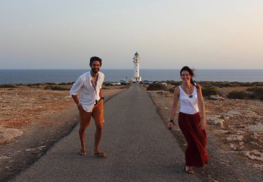 Genç güzel çiftin dikey, Cap de Barberia'nın deniz feneri yumuşak arka plan, Formentera, Balear Adaları, İspanya