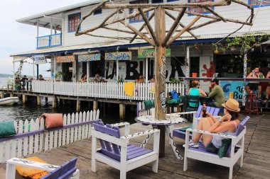 Bocas del Toro, Panama - 10 Ağustos 2014: turist ve gezginler sörf, Dalış ve güneş plaj alma uzun bir günün ardından Bocas del Toro şehir waterfront Bar ve Teras bir içeceğin tadını