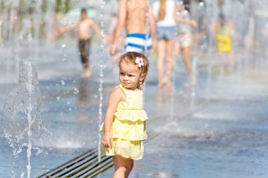 Çeşme su jetleri ile oynayan sevimli küçük kız
