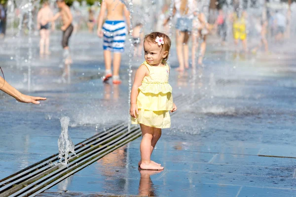 Menina bonito brincando com jatos de água da fonte — Fotografia de Stock