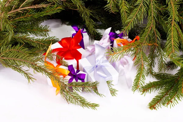 A set of Christmas gifts under fir branches on white background