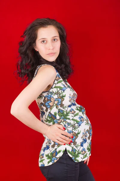 Hermosa Chica Embarazada Sobre Fondo Rojo —  Fotos de Stock