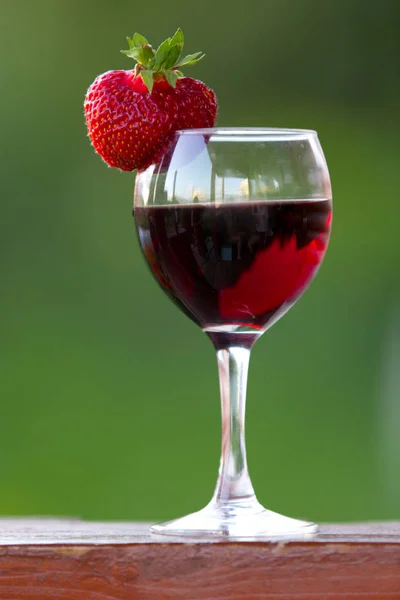 A glass of wine with strawberries outdoors