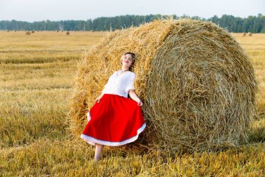 Güzel kız geleneksel kostümlü hububat sahada yürüyor