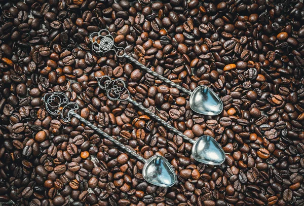 Set of vintage silver spoons on a background of coffee beans
