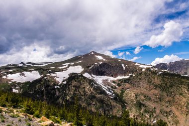 Bulutlu gökyüzü ve Rocky Dağları'nın karlı zirveleri