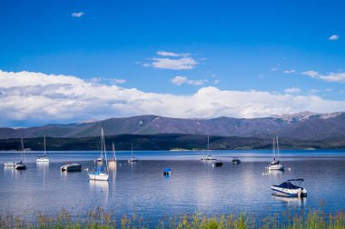 Beyaz yat, mavi gökyüzü ve mavi berrak su Grand Gölü. Rocky Dağları'nda balıkçılık